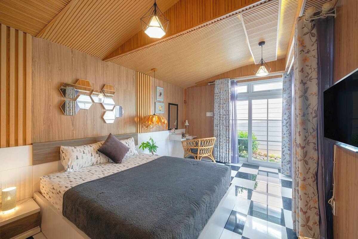 A modern hotel room with a large bed, wooden panel walls, a checkered floor, and a television.