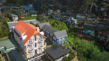 An aerial view of a residential area with multiple houses, including a prominent yellow house with a red roof and a blue house with a grey roof.