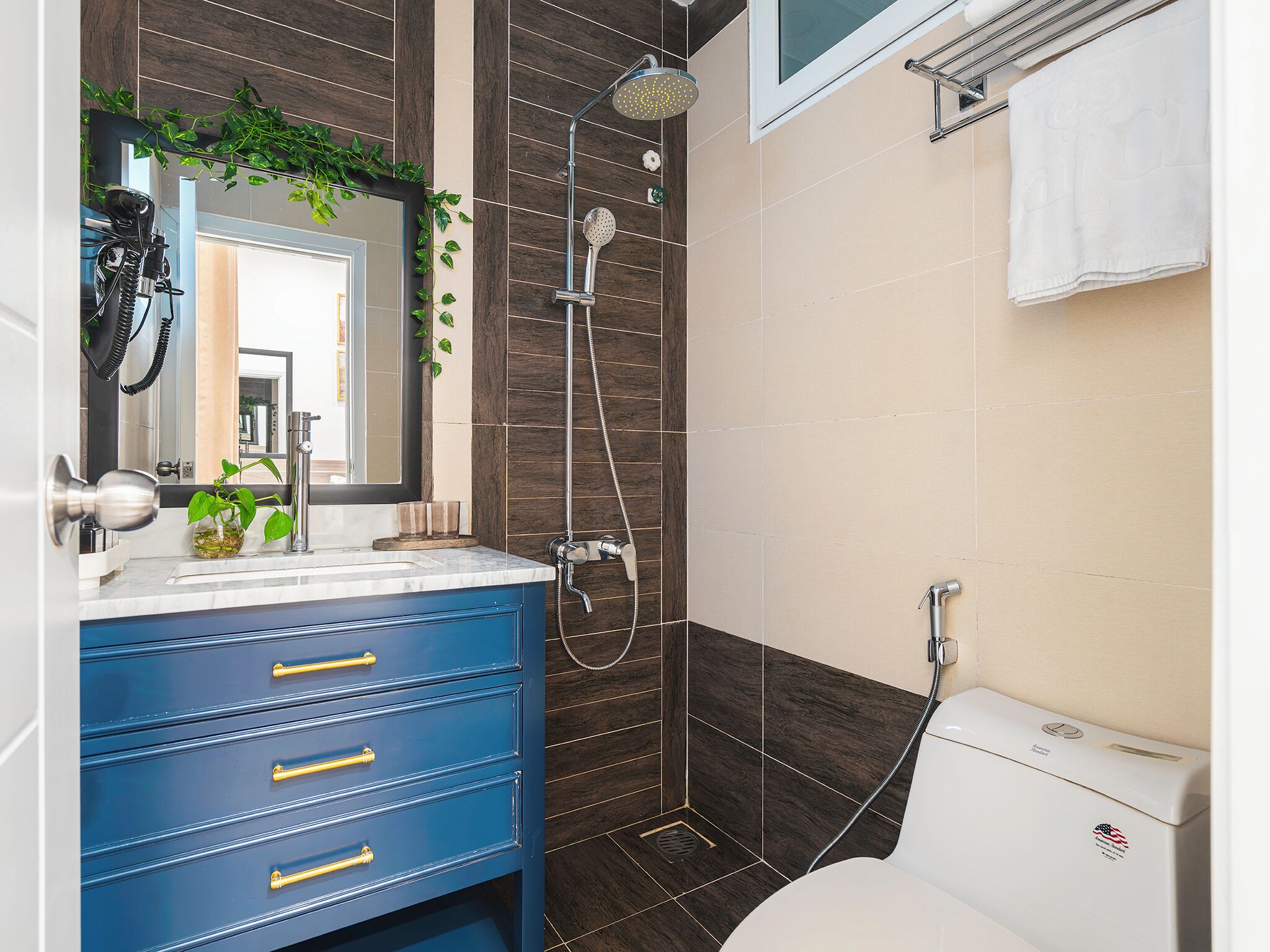 A bathroom with a shower, toilet, sink, and blue cabinetry.