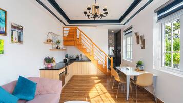 Un intérieur moderne avec un escalier en bois, un coin repas et un espace de vie comprenant un canapé et une table basse.