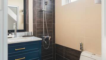 A bathroom with a shower, toilet, and vanity with drawers.