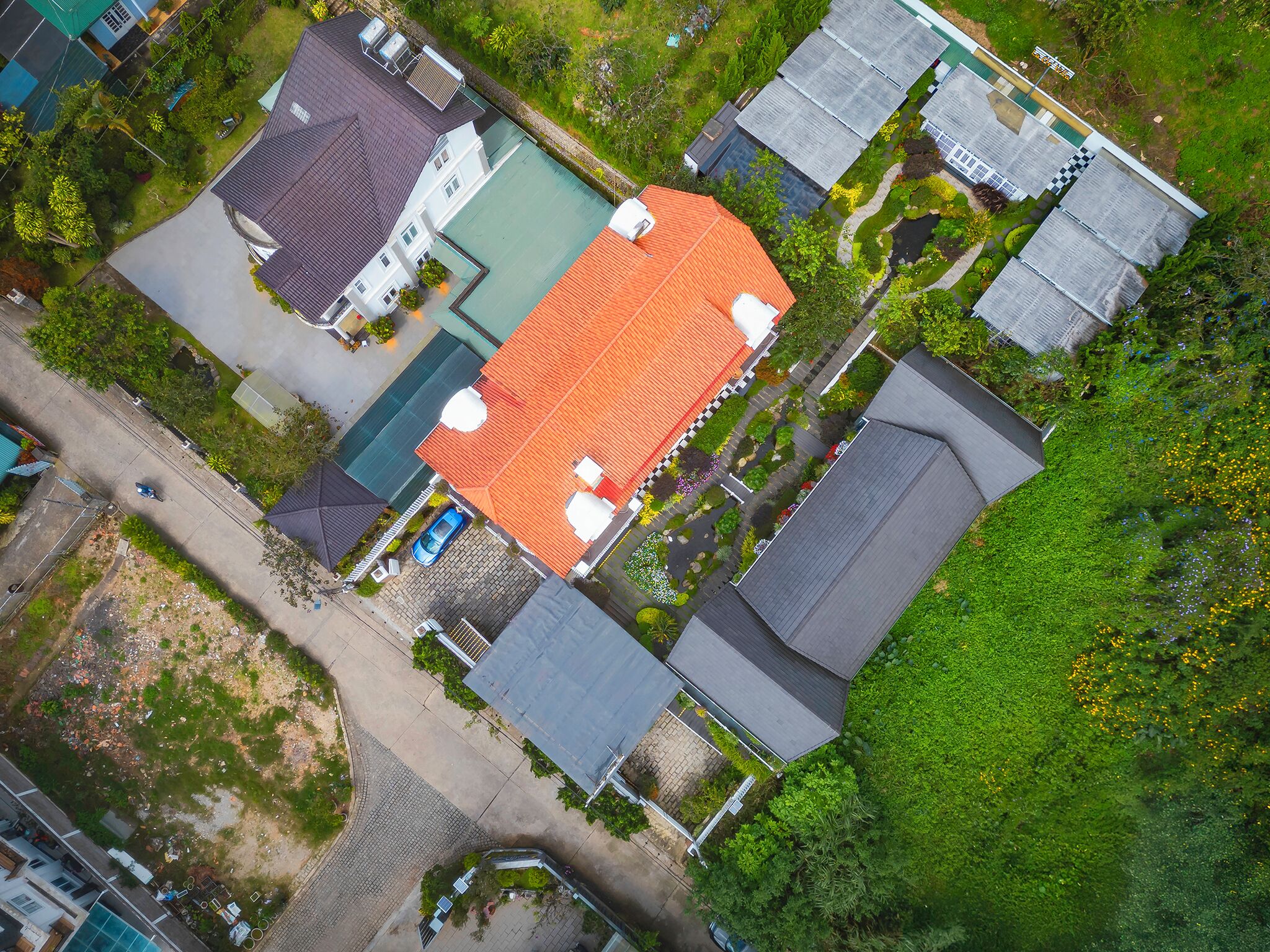 An aerial view of a residential area with multiple houses, a swimming pool, and a garden.