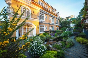 A multi-story building with a garden, a pond, and a staircase leading to the upper floors. - LACLE DALAT (Da Lat)