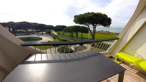 A balcony with a view of a landscaped area, a pool, and a body of water. - Apartment in Port Camargue Plage Nord sea view Swimming pool (Le Grau-du-Roi)