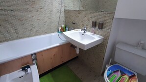 A bathroom with a bathtub, a sink, and a toilet. - Apartment in Port Camargue Plage Nord sea view Swimming pool (Le Grau-du-Roi)