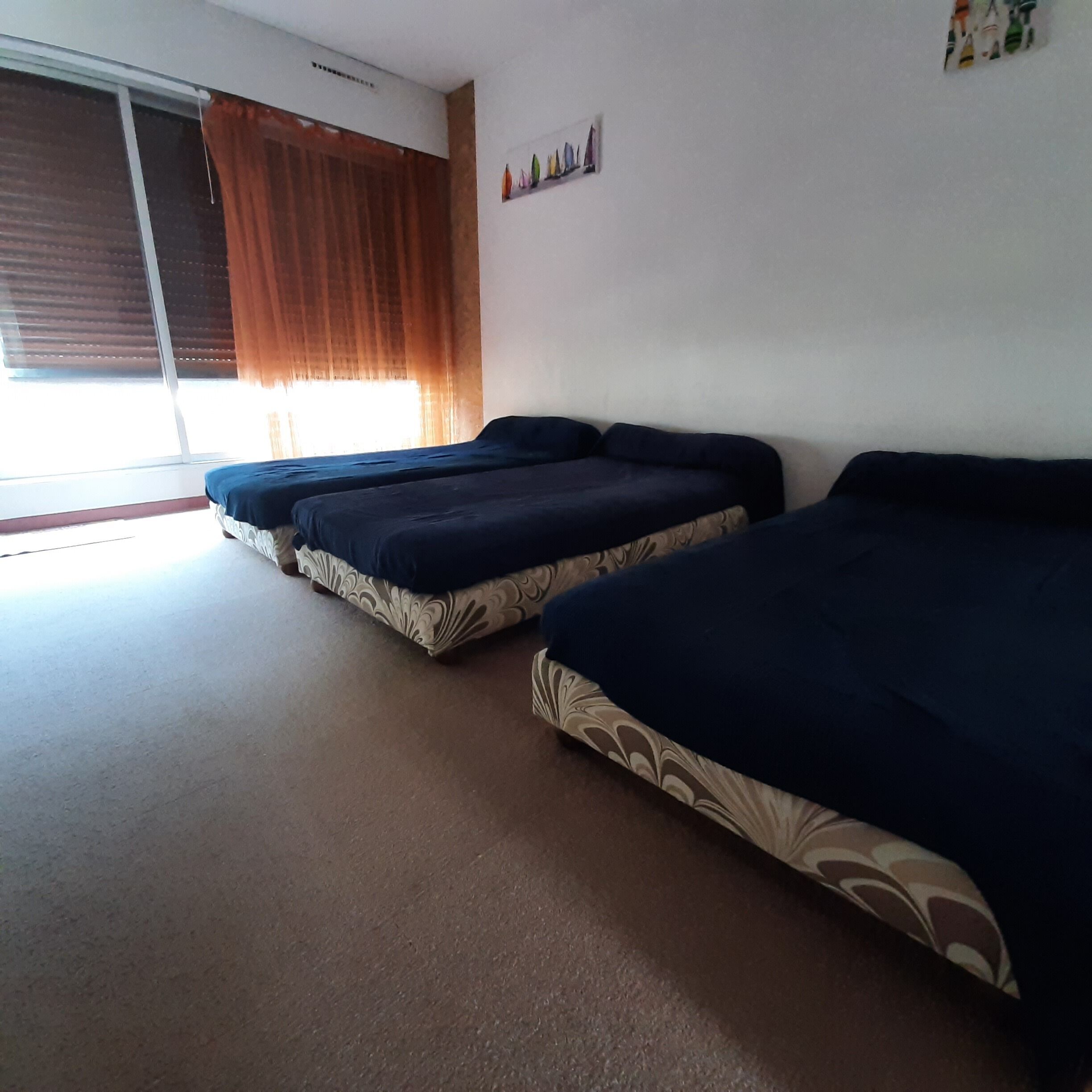 Une chambre avec deux lits, une fenêtre avec des rideaux et un élément décoratif fixé au mur.