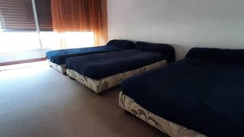 Une chambre avec deux lits, une fenêtre avec des rideaux et un élément décoratif fixé au mur.