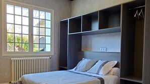 A bedroom with a bed, a window, a radiator, and built-in storage.