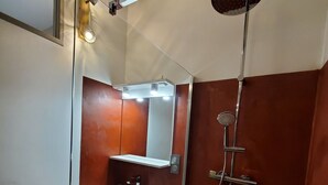 A bathroom with a white sink, mirror, and shower.