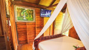 Une pièce de style cabane en bois, avec un lit, un tableau et un téléviseur accroché au mur.
