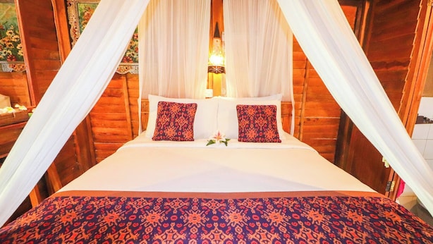Un lit à baldaquin, deux coussins à motifs et un arrangement floral.