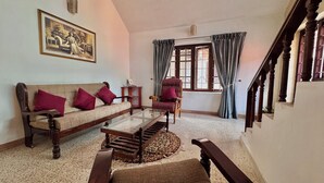 A living room with a sofa, armchair, and a coffee table. - SCARLET'S INN (Kochi)