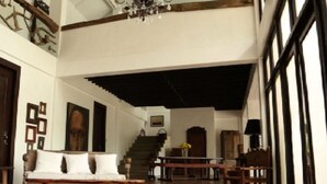 Een ruime woonkamer met een hoge plafond, een kroonluchter, een trap en uitzicht op het buitengebied.