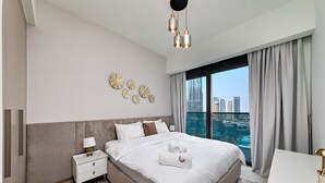 Ein modernes Hotelzimmer mit einem großen Bett, einem Nachttisch, einem Schreibtisch und Blick auf die Stadt.