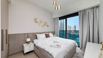 A modern hotel room with a large bed, a nightstand, a desk, and a view of the cityscape.