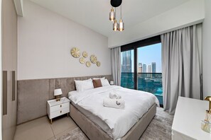 Ein modernes Hotelzimmer mit einem großen Bett, einem Nachttisch, einem Schreibtisch und Blick auf die Stadt.