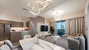 Ein modernes Wohnzimmer mit einem Esstisch aus Marmor, grauen Sofas und einem an der Wand befestigten Fernseher.
