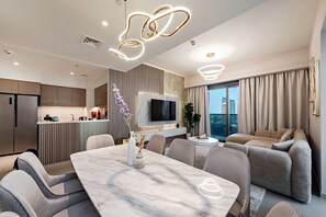 Ein modernes Wohnzimmer mit einem Esstisch aus Marmor, grauen Sofas und einem an der Wand befestigten Fernseher.