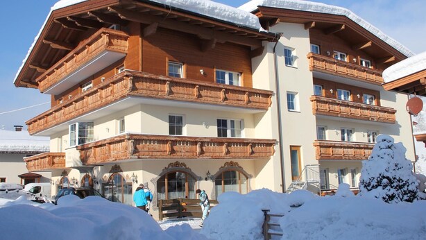 Ein mehrstöckiges Hotel mit hölzernen Balkonen und einem mit Schnee bedeckten Dach.