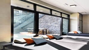 Ein modernes Interieur mit großen Fenstern, einer Steinwand und Sitzbereichen mit Kissen.