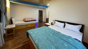 Un dormitorio con techo de madera, una cama con colcha azul estampada, una mesita de noche y un escritorio pequeño.