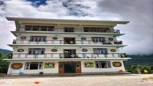 Un edificio de varios pisos con balcones, azulejos decorativos y vistas a las montañas.