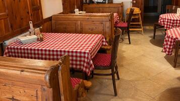 A rustic dining area with wooden tables and benches, a cash-only sign, and a WC sign.