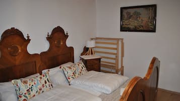 A double bed with a wooden headboard, a bedside table with a lamp, and a framed painting on the wall.
