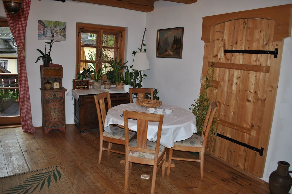 Een houten eettafel met stoelen, een houten kast, een raam en een houten deur.