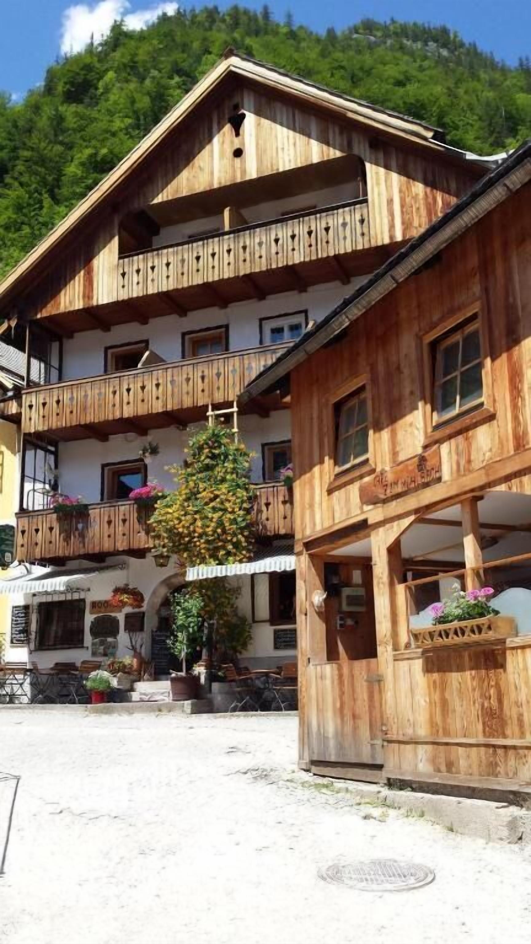 A wooden building with multiple balconies, a restaurant at the ground level, and a mountain backdrop.
