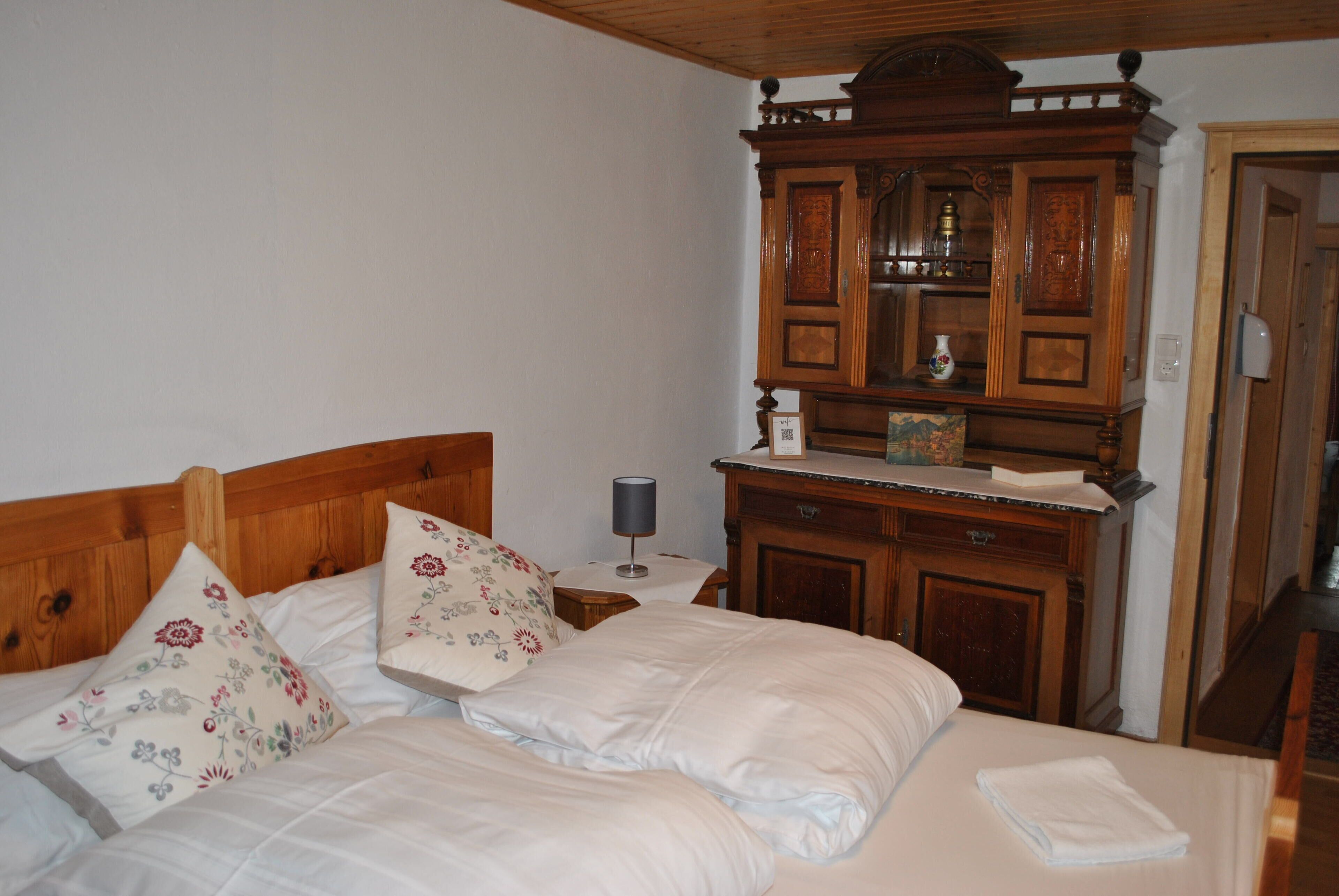 A bedroom with a wooden headboard, a wooden dresser with a mirror, and a bed with floral pillows.