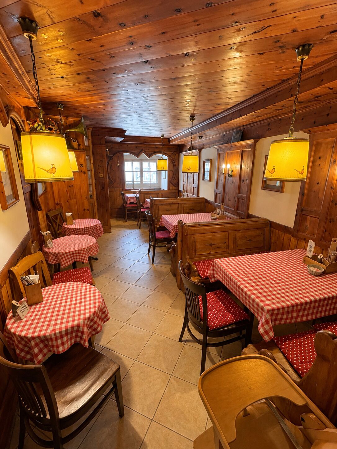 Un restaurante con interiores de madera, manteles a cuadros y lámparas colgantes.