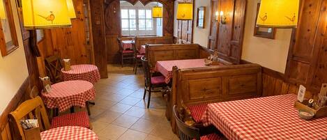 Un restaurante con interiores de madera, manteles a cuadros y lámparas colgantes.
