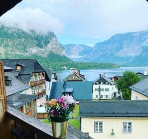 Vue d’un village au bord d’un lac, avec ses bâtiments traditionnels et une chaîne de montagnes en arrière-plan.