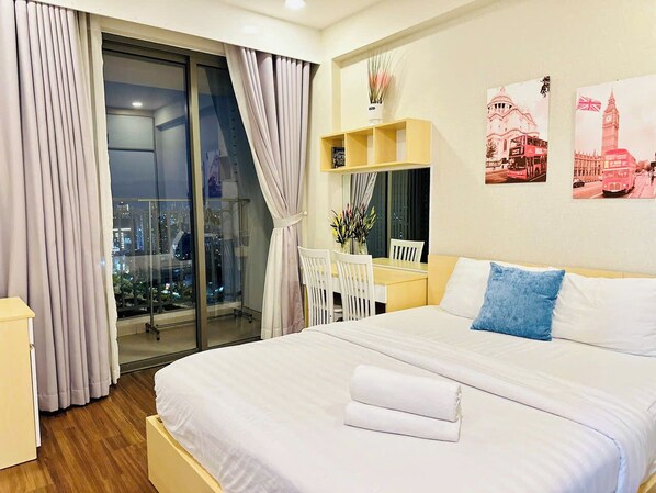 Habitación de hotel con una cama grande, un escritorio y una silla, vista del paisaje urbano a través de la ventana y obras de arte en la pared.