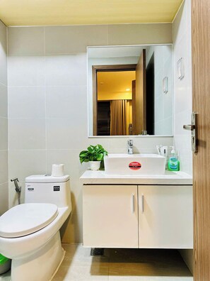 Un baño con inodoro, lavabo, espejo y mueble.