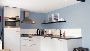 Een moderne keuken met witte kastjes, een roestvrijstalen afzuigkap, een ingebouwde oven en een zwart aanrecht.