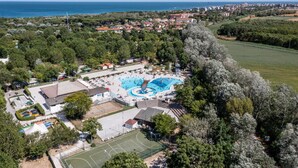 Vista aérea de un resort con una amplia piscina, canchas de tenis y acceso directo a la playa.