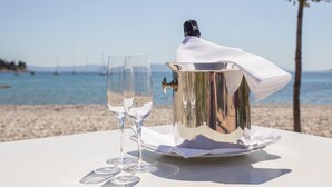 A table with a champagne bucket and glasses on a beach with a clear view of the sea and boats in the background. - Mobile home in Rabac with shared pool (Rabac)