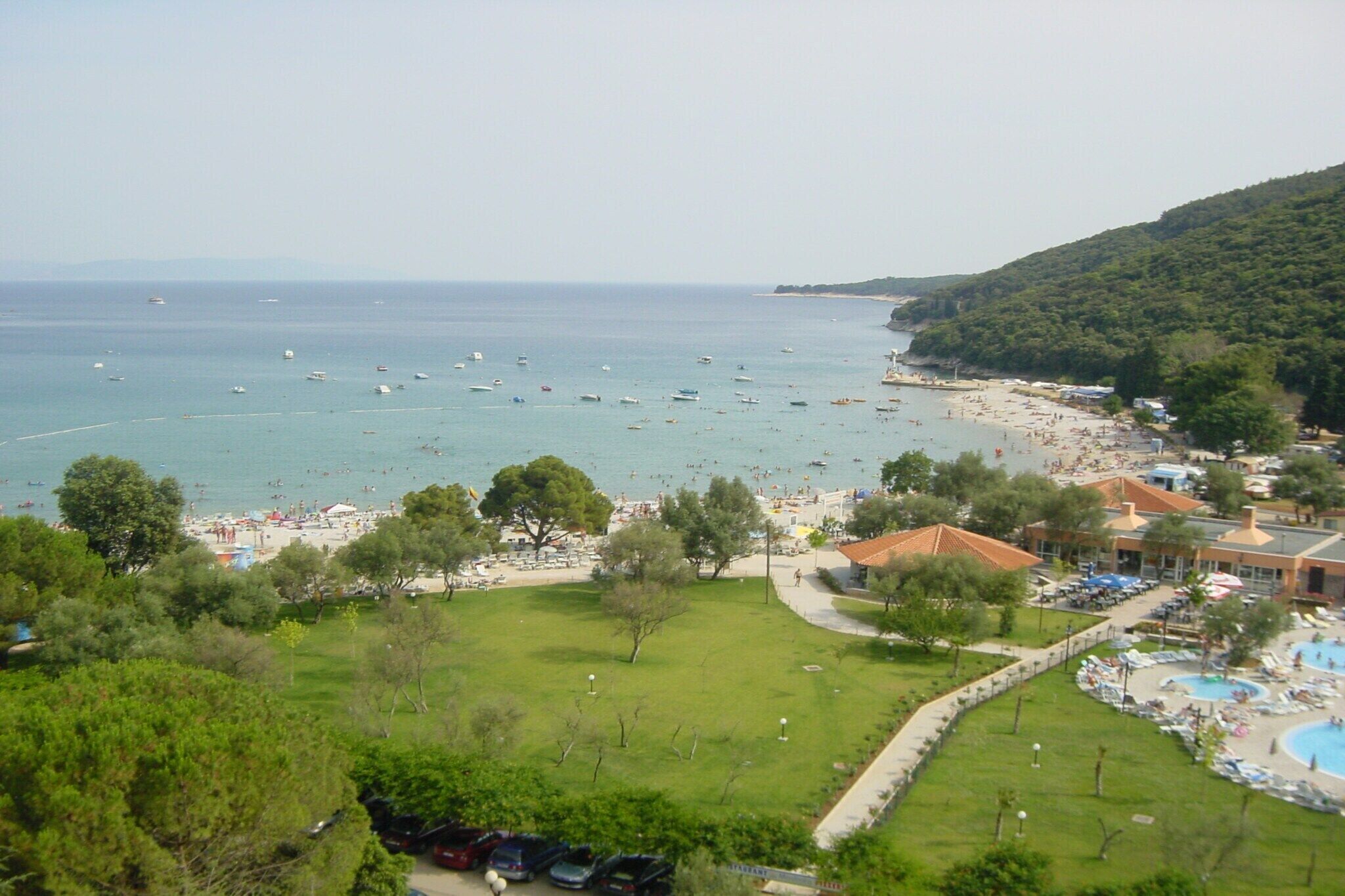 A coastal resort with a beach, swimming pool, and lush greenery.