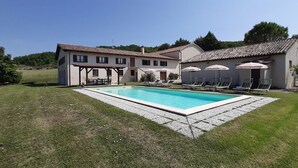 Ein zweistöckiges Haus mit Swimmingpool, Sitzgelegenheiten im Freien und einem Garten.