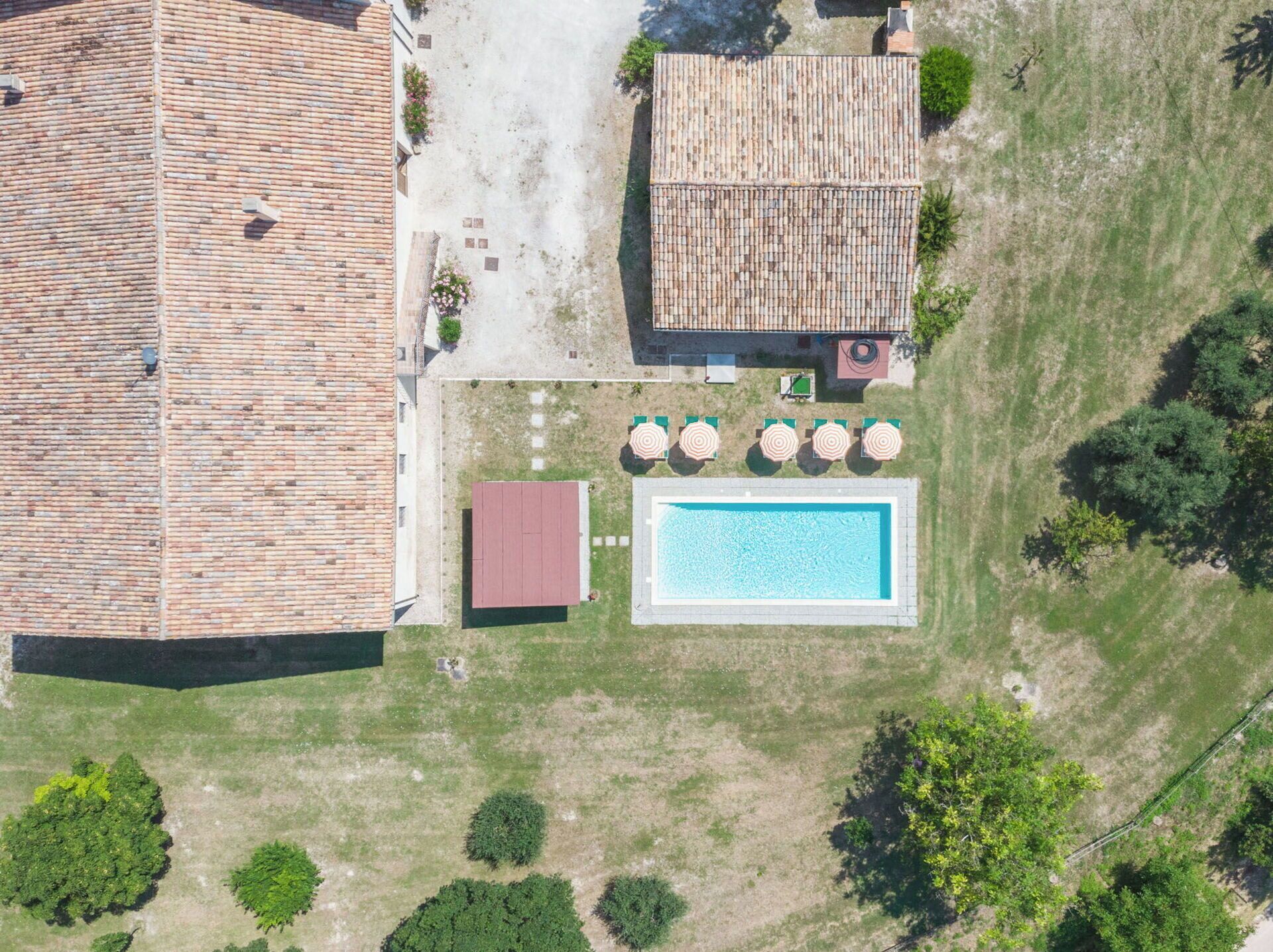 Vue aérienne d’une propriété dotée d’une piscine, d’un patio couvert et d’un bâtiment dont le toit est en briques.
