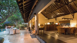 A covered outdoor dining area with a pool, stone walls, and wooden flooring. - Peacefully, 3 Bedroom Villa in Seminyak (Seminyak)