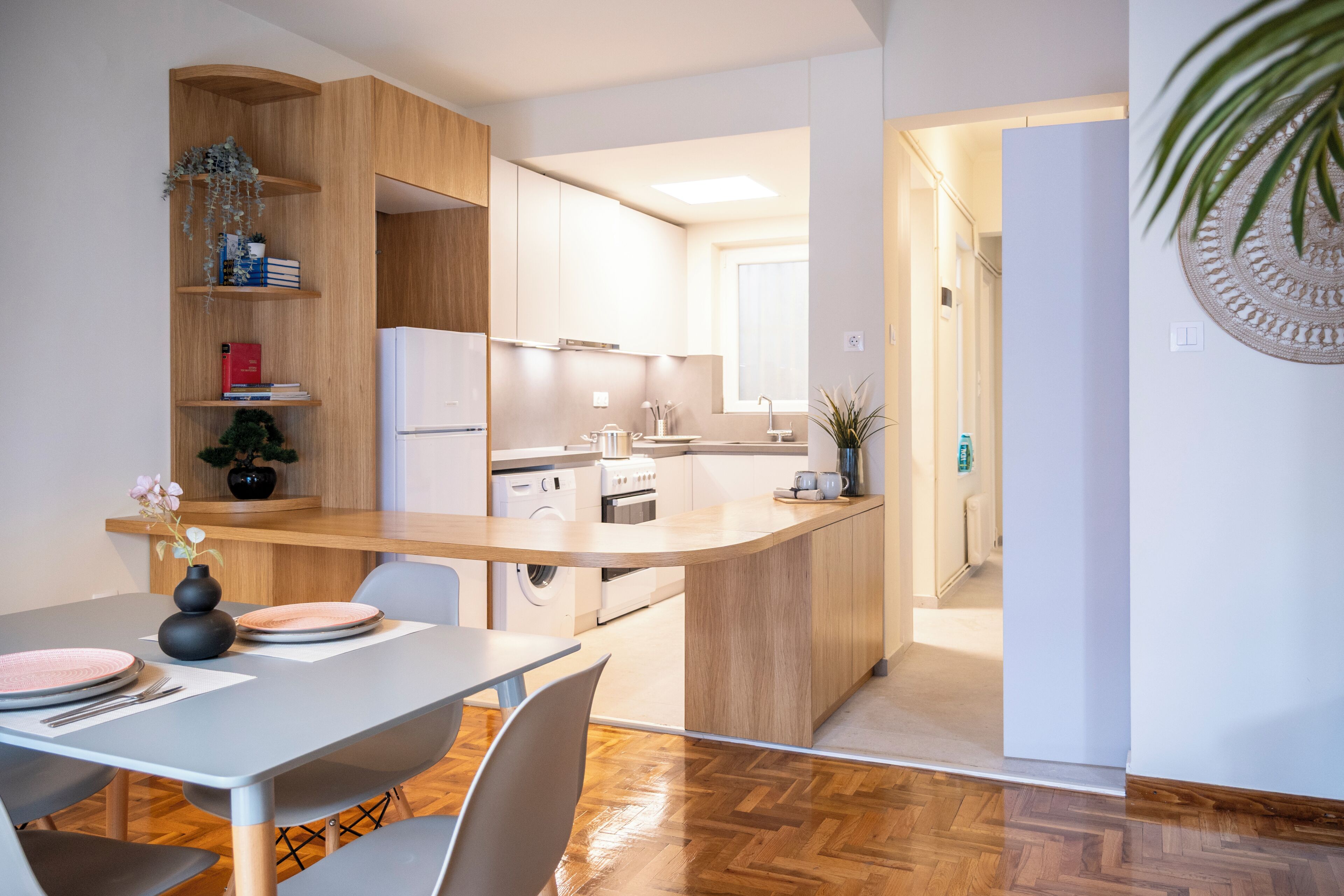 A modern kitchen with a central island, built-in appliances, and a dining area with a table and chairs.