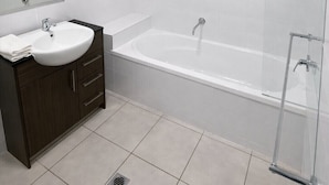 Un bagno moderno con un lavandino bianco, un mobile contenitore in legno scuro e una cabina doccia in vetro.