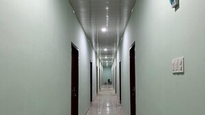 Un long couloir étroit, avec des portes de chaque côté, un mur vert clair et un sol brillant.