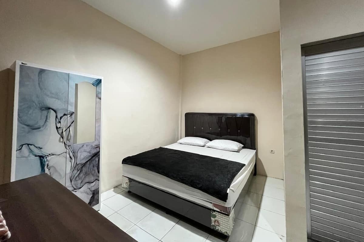 A bedroom with a bed, a dresser, and a door with a mirror.