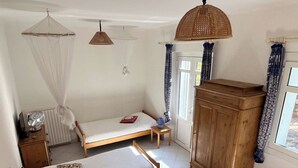 Pieni, viihtyisä huone, jossa on kaksi erillistä sänkyä, puinen kaappi ja kattotuuletin.