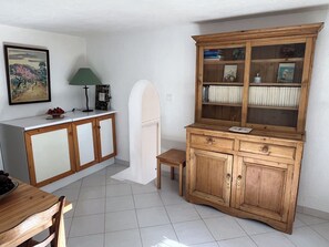 A kitchen with wooden cabinets, a white countertop, a small table, and a chair. - Villa Fiori di Melu - House in Palombaggia - Five minutes walk from the beach (Porto-Vecchio)
