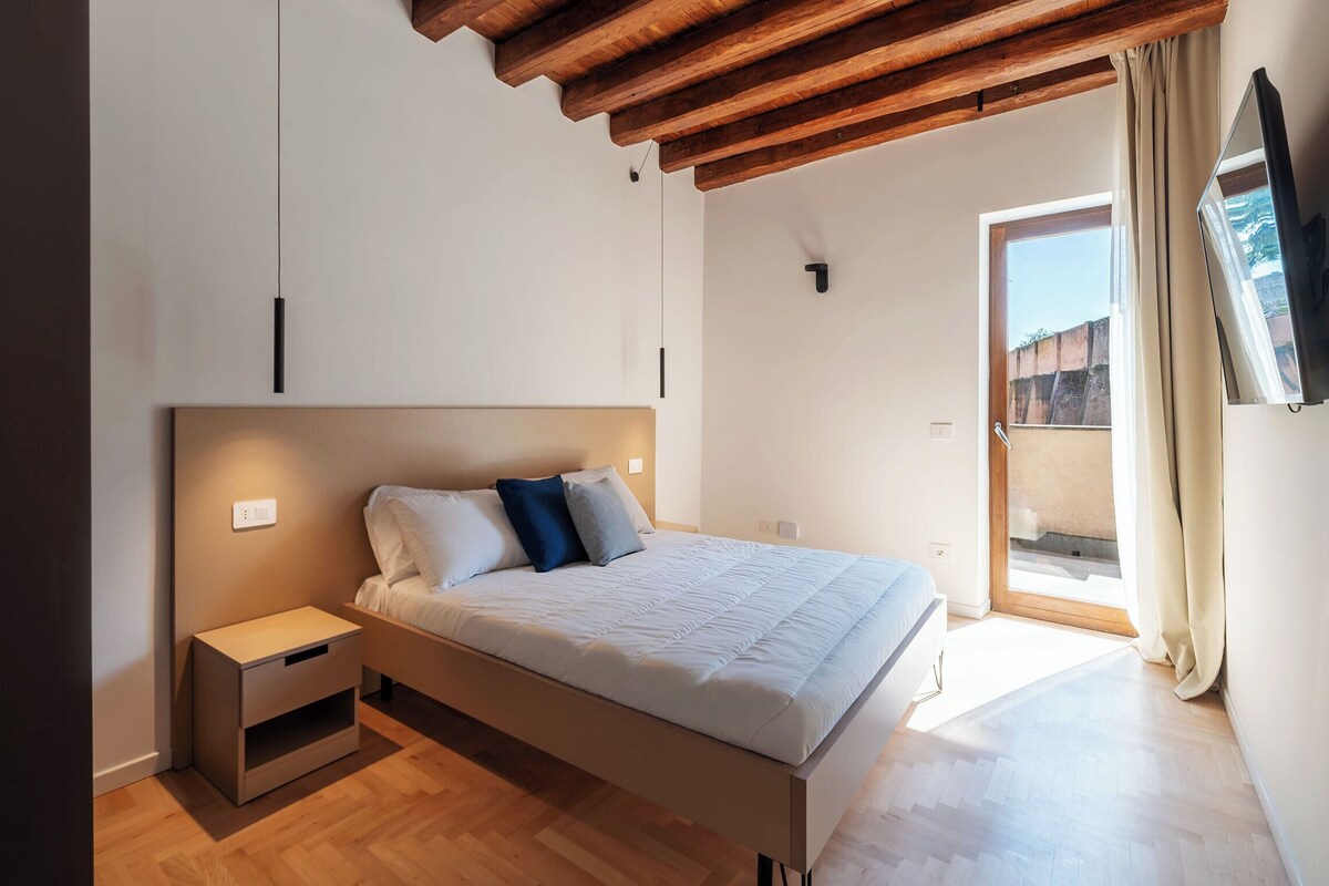 A bedroom with a bed, bedside table, and a window with curtains.